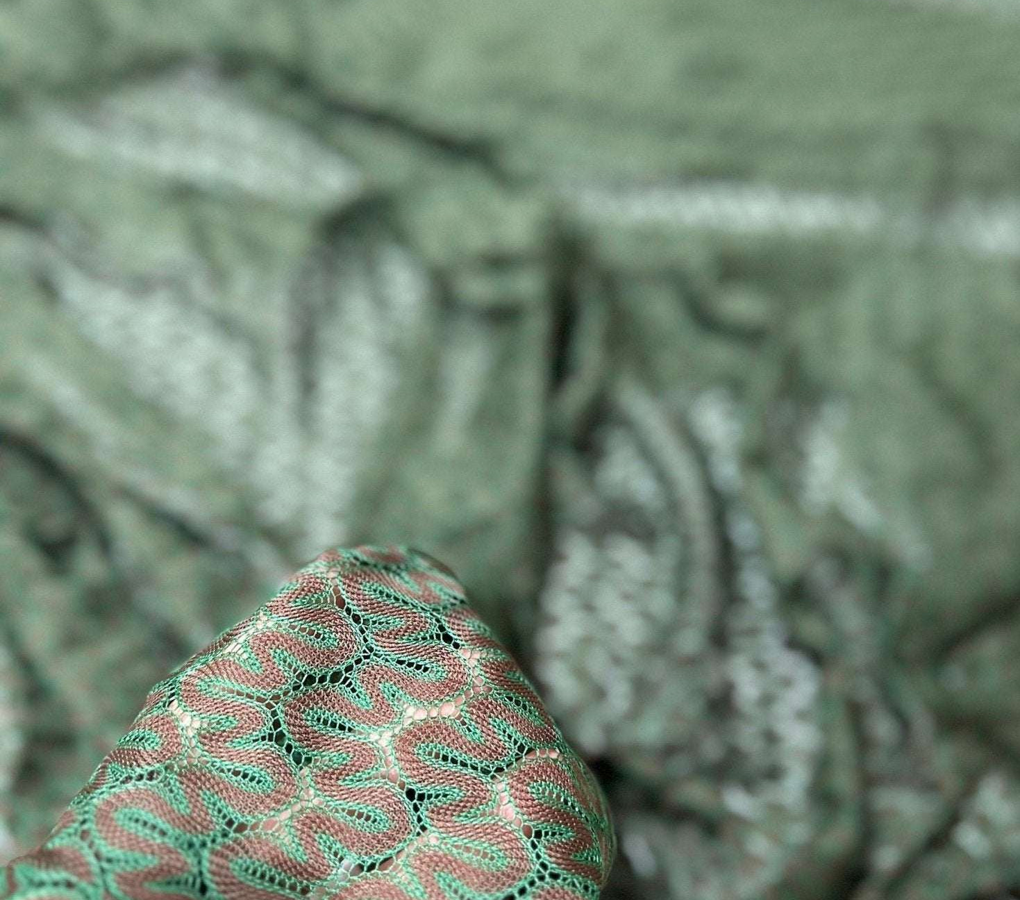 Close-up of green and brown zigzag knit jersey mesh fabric held in hand showing texture and pattern