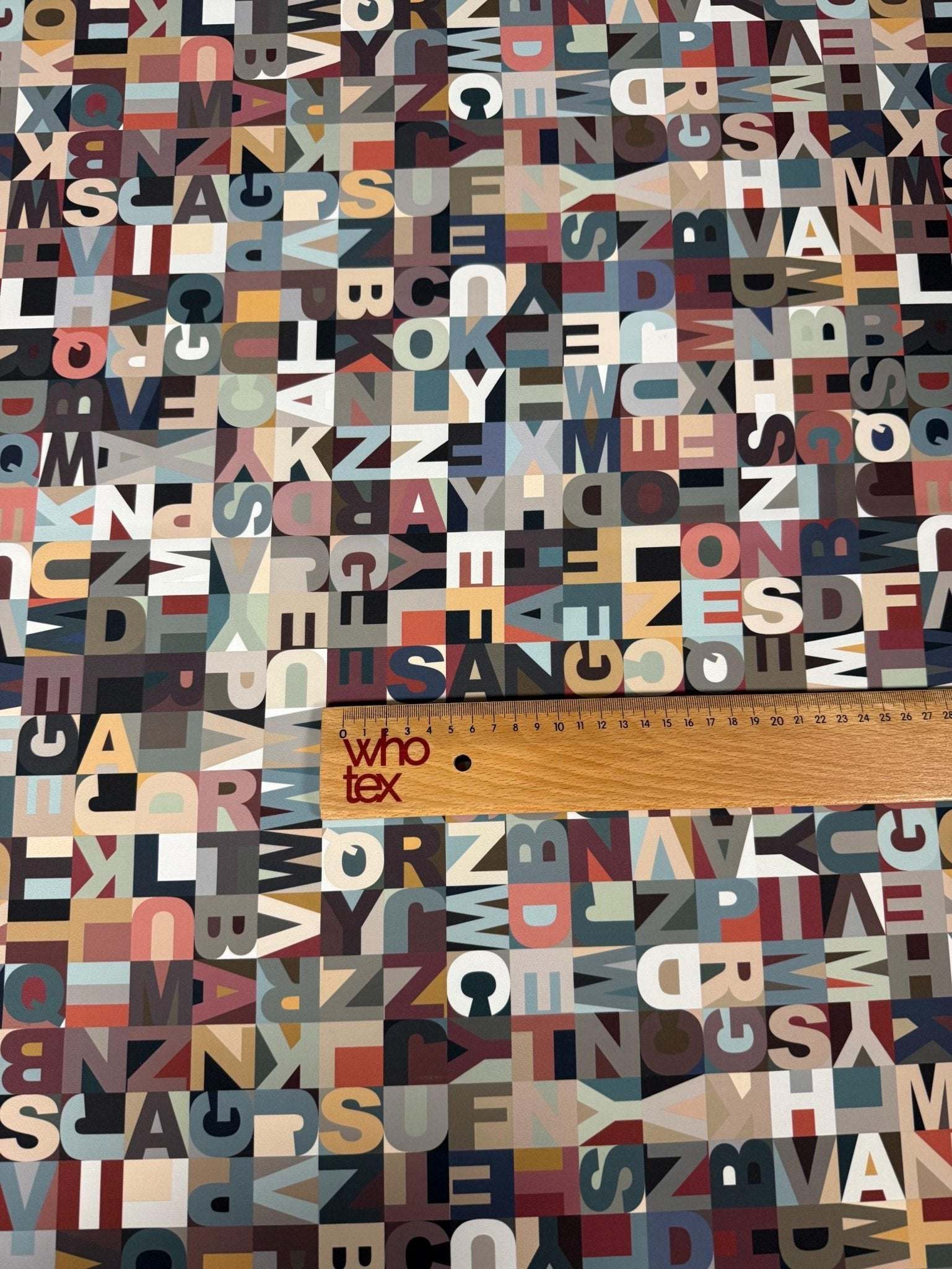Colorful modern alphabet pattern fabric with varied typography design and ruler for scale