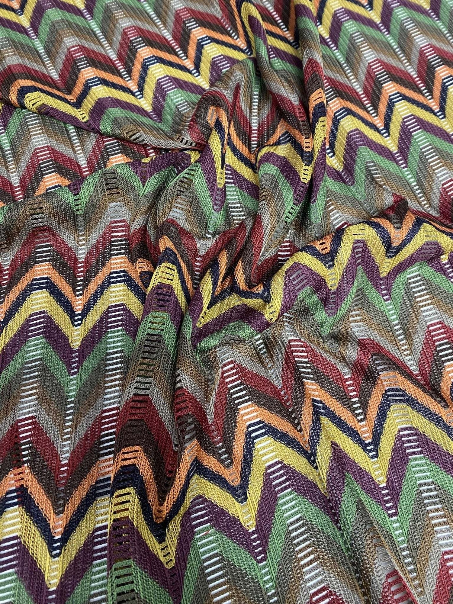 Multicolor chevron jacquard fabric with zigzag knit pattern in green, yellow, purple, and orange tones.